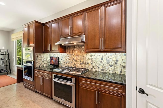 kitchen featuring backsplash, light tile patterned floors, dark stone counters, and stainless steel gas stovetop