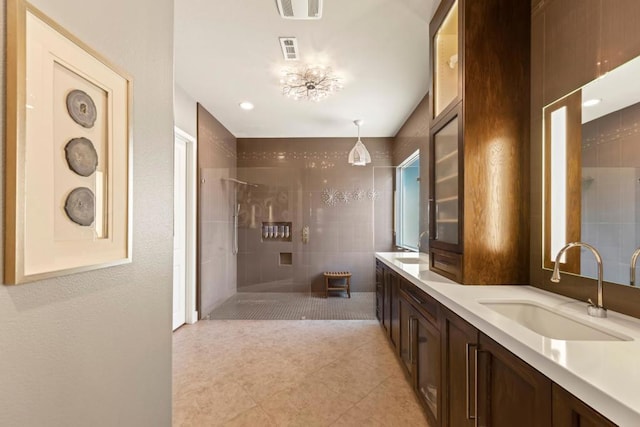 bathroom featuring tiled shower, vanity, and tile patterned flooring