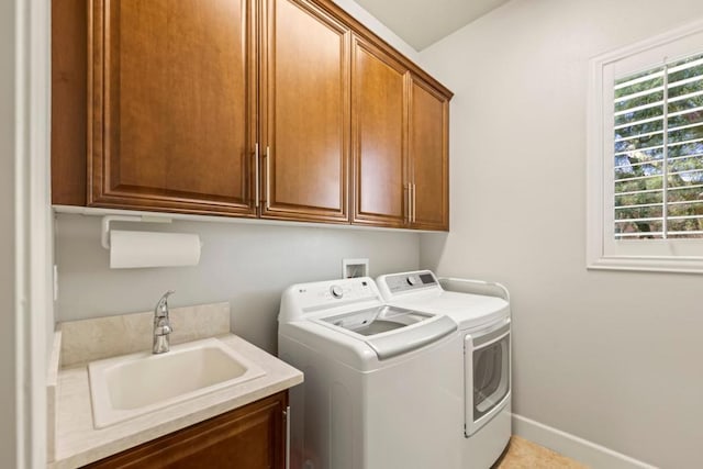 laundry area featuring washing machine and clothes dryer, sink, light tile patterned floors, and cabinets