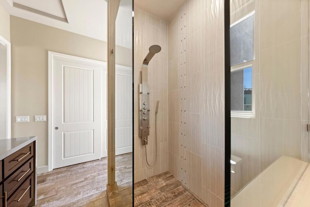 bathroom featuring wood-type flooring, vanity, and a tile shower