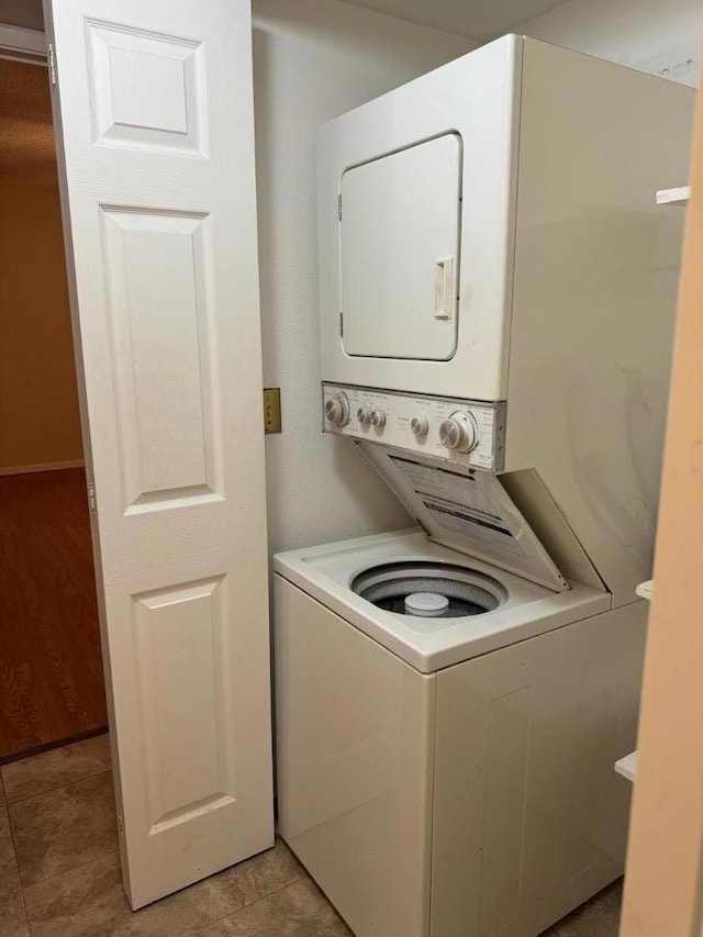 clothes washing area featuring light tile patterned floors and stacked washer / drying machine