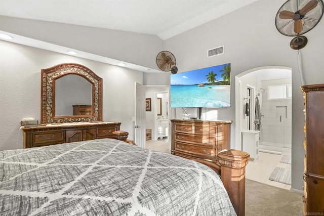 bedroom with light colored carpet, lofted ceiling, and connected bathroom