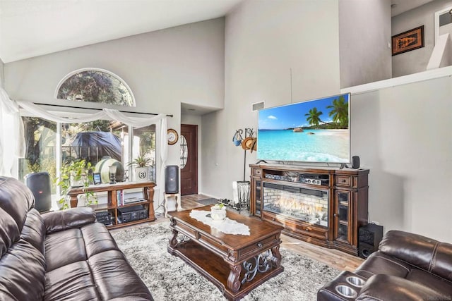 living room with light wood-type flooring and high vaulted ceiling