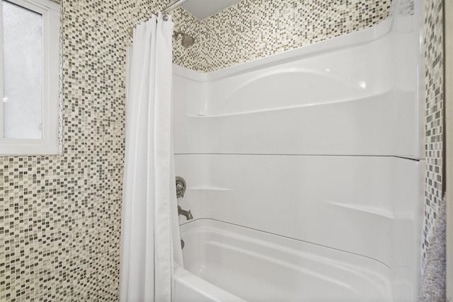 bathroom with shower / bath combo with shower curtain, a healthy amount of sunlight, and tile walls