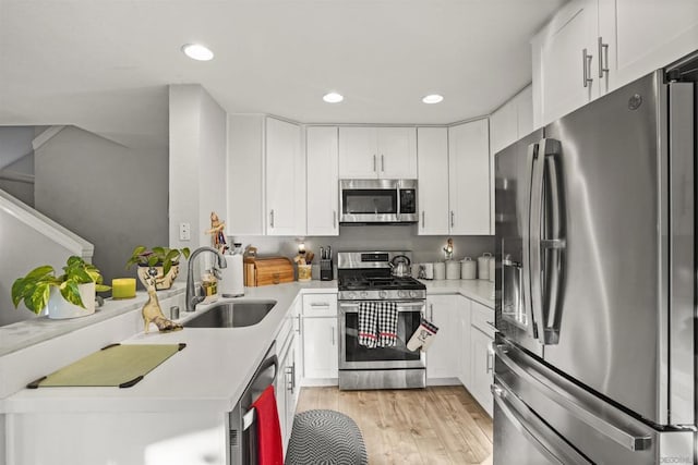 kitchen featuring white cabinets, sink, stainless steel appliances, and light hardwood / wood-style flooring