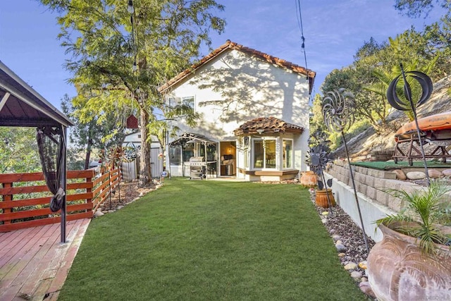 rear view of house with a deck and a yard