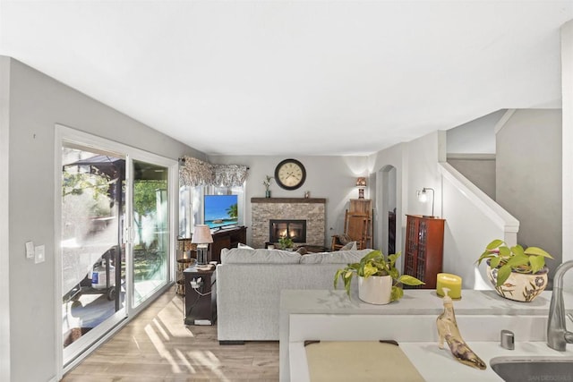 living room featuring light hardwood / wood-style floors, a stone fireplace, and sink