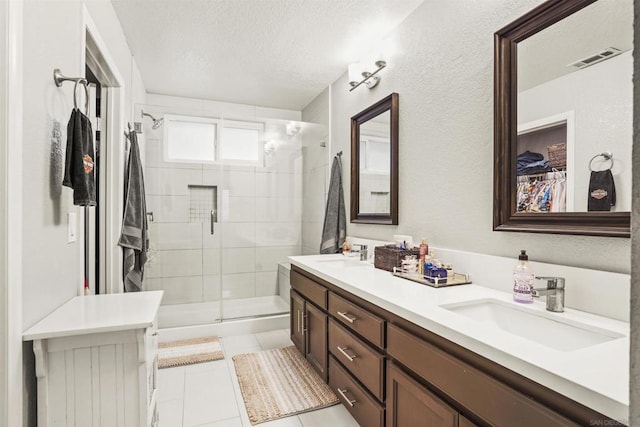 bathroom with tile patterned flooring, vanity, an enclosed shower, and a textured ceiling