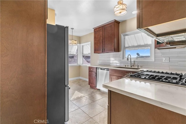 kitchen with sink, light tile patterned floors, tasteful backsplash, decorative light fixtures, and stainless steel appliances