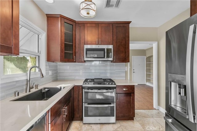 kitchen with light stone countertops, sink, light hardwood / wood-style floors, decorative backsplash, and appliances with stainless steel finishes