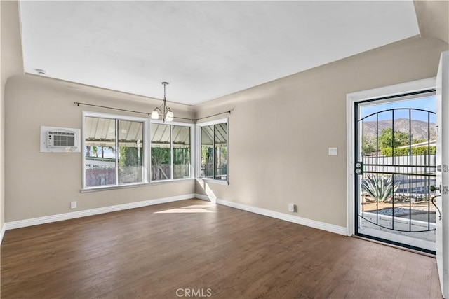 unfurnished room with a notable chandelier, dark hardwood / wood-style floors, and an AC wall unit