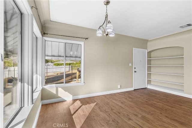 unfurnished dining area with wood-type flooring and an inviting chandelier