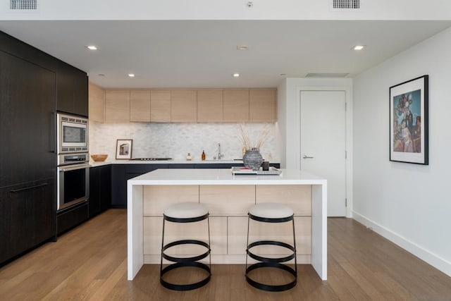 kitchen featuring stainless steel appliances, a kitchen island, and light hardwood / wood-style flooring