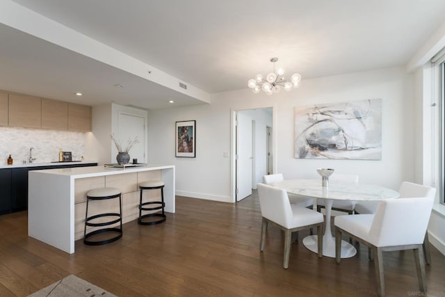 dining space with dark hardwood / wood-style floors, sink, and a chandelier