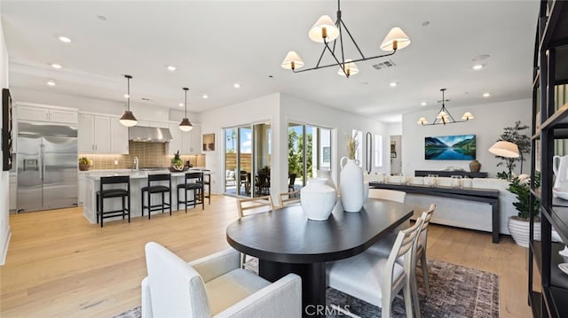 dining area featuring sink, an inviting chandelier, and light wood-type flooring