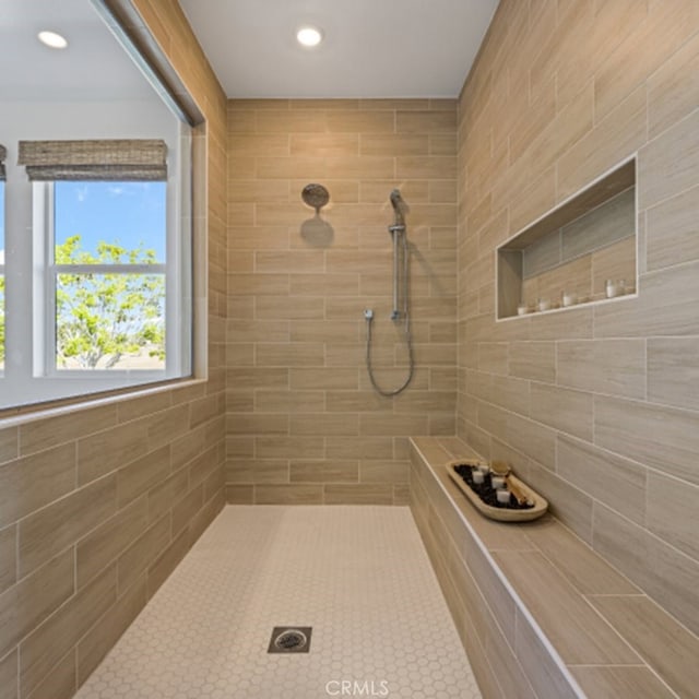 bathroom featuring a tile shower and tile walls