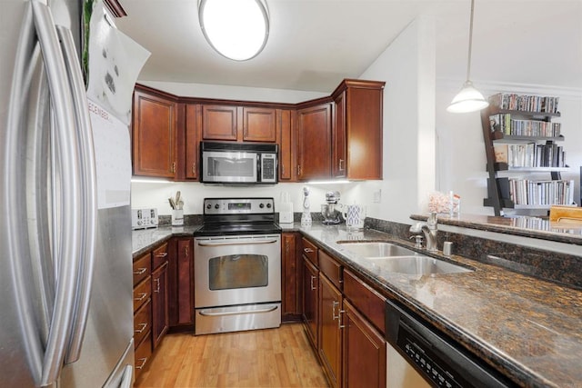 kitchen featuring decorative light fixtures, sink, appliances with stainless steel finishes, and dark stone counters