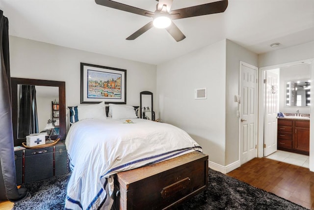 bedroom featuring light wood-type flooring, ceiling fan, ensuite bathroom, and sink