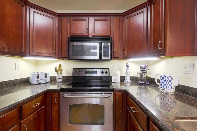 kitchen featuring appliances with stainless steel finishes and dark stone countertops