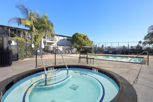 view of swimming pool featuring a hot tub and a patio area