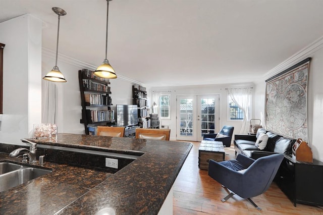 kitchen featuring hardwood / wood-style flooring, decorative light fixtures, french doors, ornamental molding, and sink