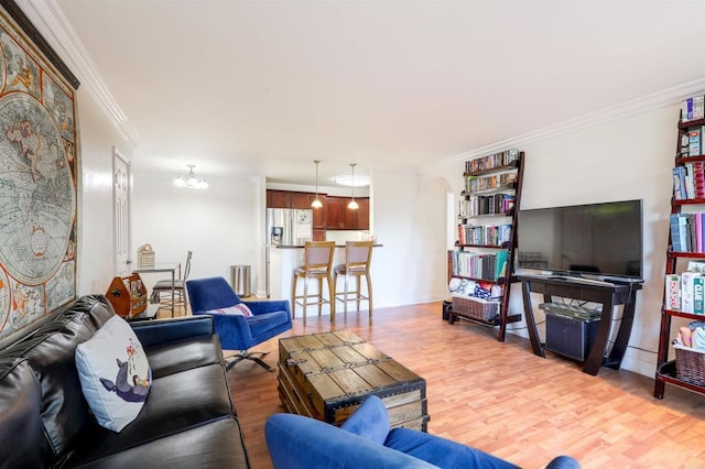 living room with an inviting chandelier, crown molding, and light hardwood / wood-style floors