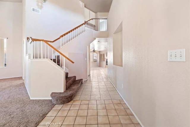 interior space featuring ceiling fan, a towering ceiling, and tile patterned floors