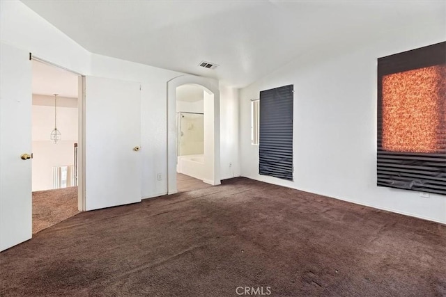 empty room featuring dark carpet and lofted ceiling