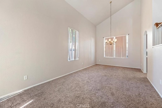 empty room with high vaulted ceiling, an inviting chandelier, and carpet flooring