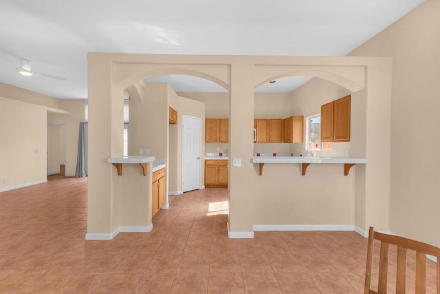 kitchen with kitchen peninsula, light tile patterned floors, and a kitchen breakfast bar