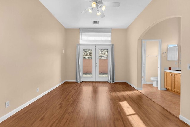 empty room with ceiling fan, french doors, and light wood-type flooring