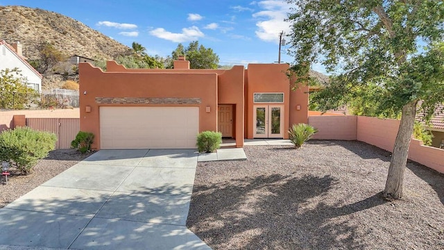 pueblo-style house with a mountain view, a garage, and french doors