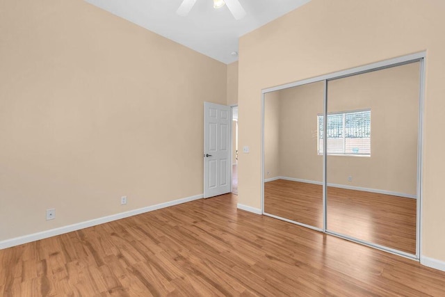 unfurnished bedroom featuring light wood-type flooring, high vaulted ceiling, a closet, and ceiling fan