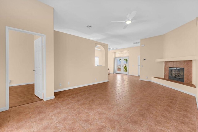 unfurnished living room with ceiling fan, light tile patterned flooring, and a fireplace