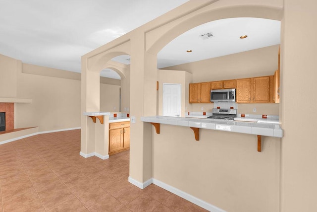 kitchen featuring a fireplace, stainless steel appliances, kitchen peninsula, and a breakfast bar area