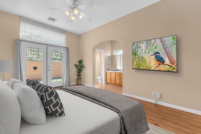 bedroom featuring multiple windows, ceiling fan, light hardwood / wood-style flooring, and ensuite bathroom