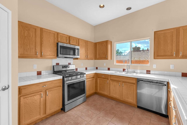 kitchen featuring appliances with stainless steel finishes, tile countertops, light tile patterned floors, and sink