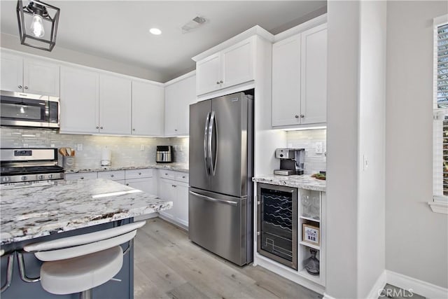 kitchen featuring white cabinets, wine cooler, backsplash, and appliances with stainless steel finishes