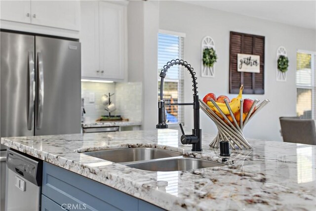 kitchen with blue cabinetry, white cabinets, sink, and stainless steel appliances