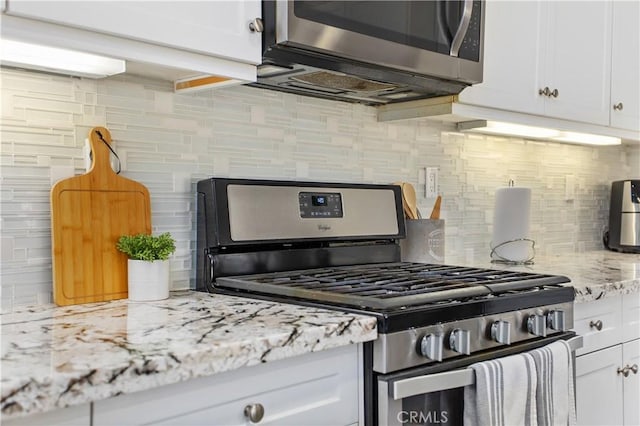 kitchen featuring backsplash, light stone countertops, white cabinetry, and stainless steel appliances