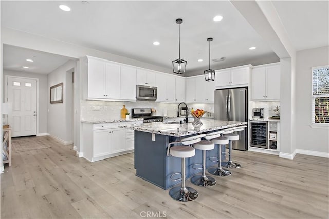 kitchen featuring white cabinets, appliances with stainless steel finishes, a kitchen island with sink, and sink