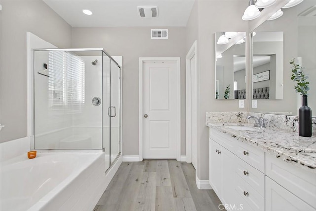 bathroom with separate shower and tub, vanity, and hardwood / wood-style flooring