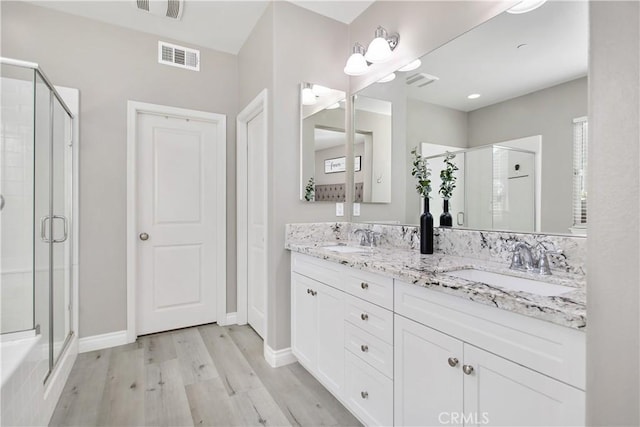 bathroom featuring wood-type flooring, vanity, and a shower with door