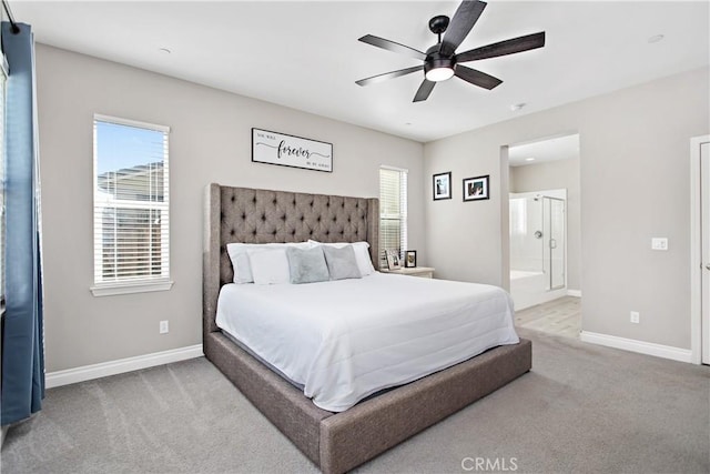 bedroom with multiple windows, light colored carpet, ensuite bath, and ceiling fan