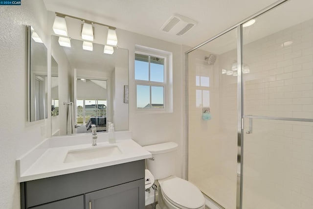 bathroom with vanity, toilet, and a shower with door