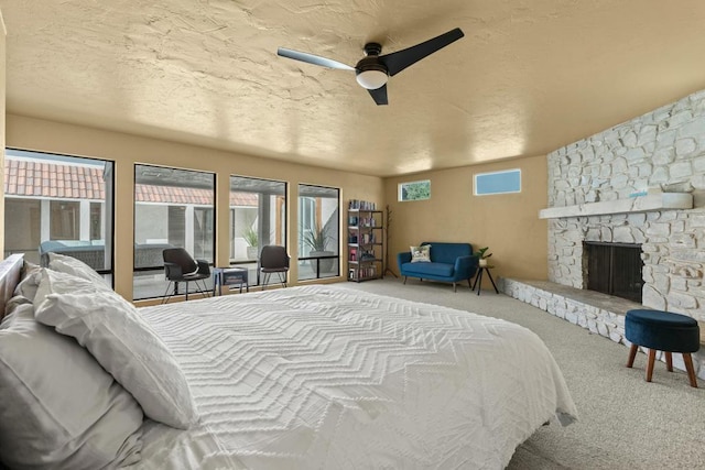 carpeted bedroom featuring a textured ceiling, ceiling fan, a fireplace, and multiple windows