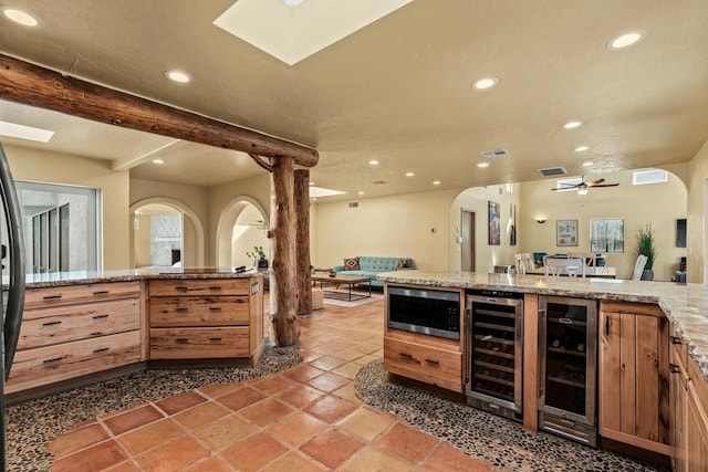 bar featuring ceiling fan, stainless steel microwave, and beverage cooler