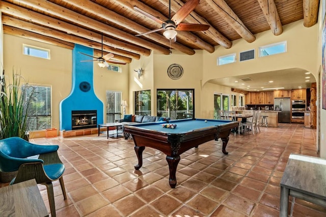 playroom with wooden ceiling, a tile fireplace, a high ceiling, pool table, and beamed ceiling