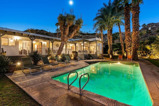 pool at dusk featuring a patio area