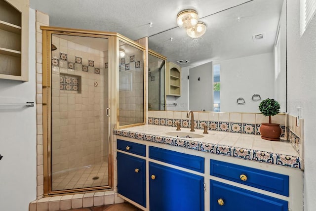 bathroom featuring vanity, a textured ceiling, backsplash, and walk in shower